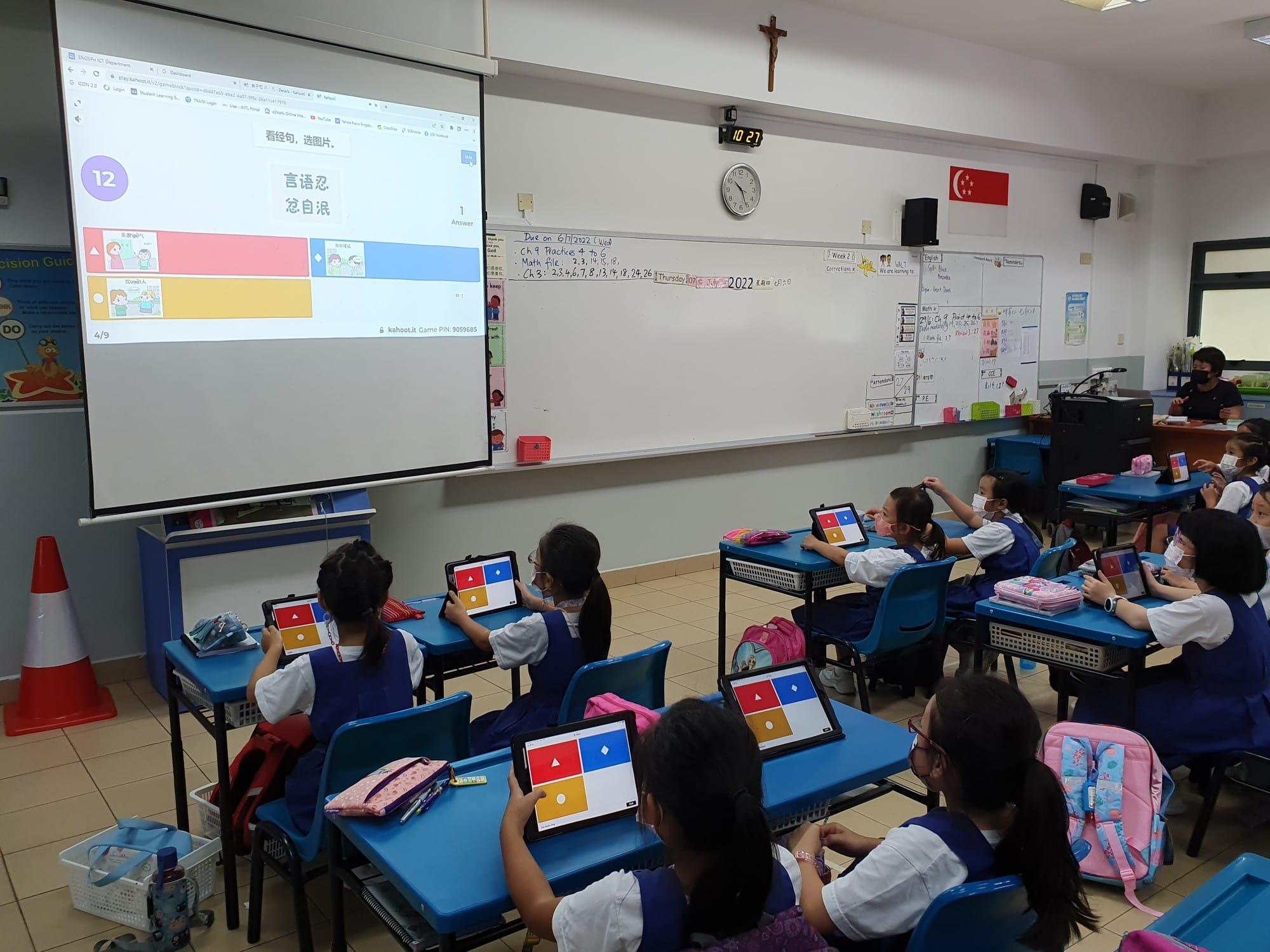 Young students in blue uniforms use tablets playing Kahoot in a classroom with a projected Chinese quiz on screen.